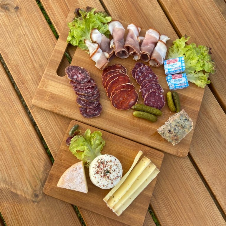 Planches de bois garnies de charcuterie, fromages, cornichons et beurre fermier